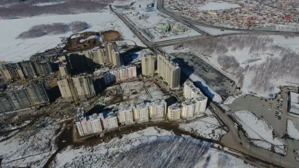Construcción de una nueva zona residencial frente al tráfico rodado cubierto de nieve . — Vídeos de Stock