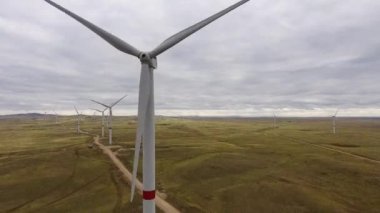 Bir tarladaki büyük bir rüzgar türbininin pervanelerini ufuktaki turuncu günbatımının arka planına doğru hareket ettir. Alternatif enerji kaynakları. Rüzgarlı park. Ekolojik enerji. Sanayi.