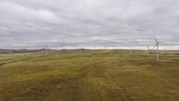 Pohybovat čepele velké větrné turbíny v poli na pozadí oranžového západu slunce na obzoru s krásnými kopci. Alternativní zdroje energie. Větrný park. Ekologická energie.Průmyslová — Stock video