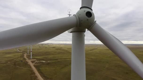 Mova as lâminas de uma grande turbina eólica em um campo contra um fundo de pôr-do-sol laranja no horizonte com uma bela serra. Fontes de energia alternativas. Parque ventoso. Energia ecológica.Industrial — Vídeo de Stock