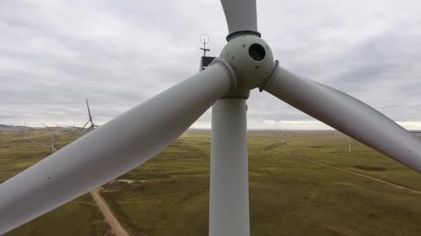 Bewegen Sie die Flügel einer großen Windkraftanlage auf einem Feld vor dem Hintergrund eines orangefarbenen Sonnenuntergangs am Horizont mit einem wunderschönen Hügel. Alternative Energiequellen. Windiger Park. Ökologische Energie.Industrie — Stockvideo