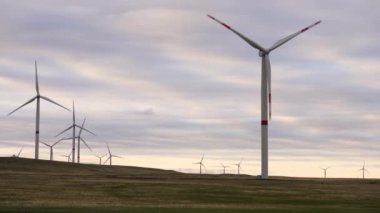 Bir tarladaki büyük bir rüzgar türbininin pervanelerini ufuktaki turuncu günbatımının arka planına doğru hareket ettir. Alternatif enerji kaynakları. Rüzgarlı park. Ekolojik enerji. Sanayi.