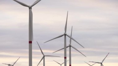 Bir tarladaki büyük bir rüzgar türbininin pervanelerini ufuktaki turuncu günbatımının arka planına doğru hareket ettir. Alternatif enerji kaynakları. Rüzgarlı park. Ekolojik enerji. Sanayi.
