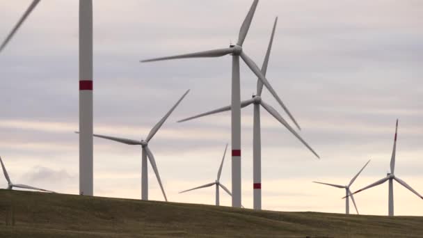 Beweeg de bladen van een grote windturbine in een veld tegen een achtergrond van oranje zonsondergang aan de horizon met een prachtige heuvels. Alternatieve energiebronnen. Winderig park. Ecologische energie.Industrieel — Stockvideo