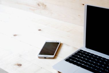 Laptop ve ahşap bir masa akıllı telefon.