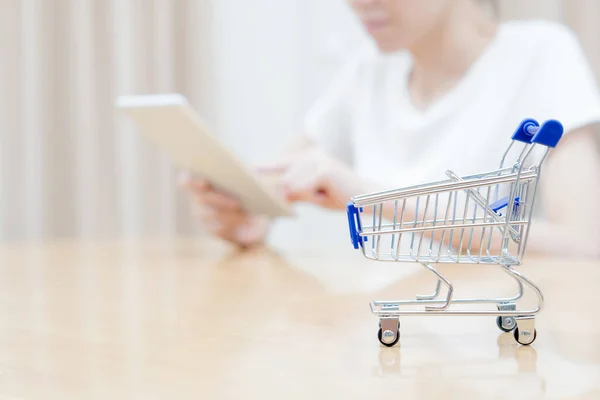 Donna che fa shopping alla scrivania con carrello in miniatura — Foto Stock