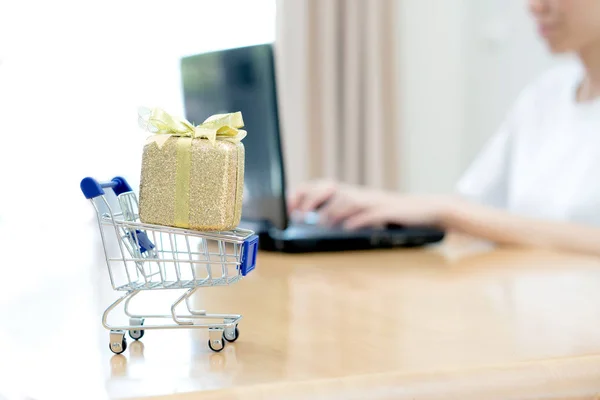 Hand houden laptop met kleine winkelwagen — Stockfoto