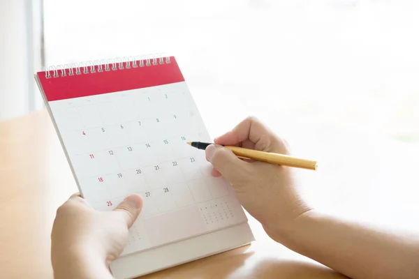Woman hand carrying calendar and pointing on it by pen — Stock Photo, Image