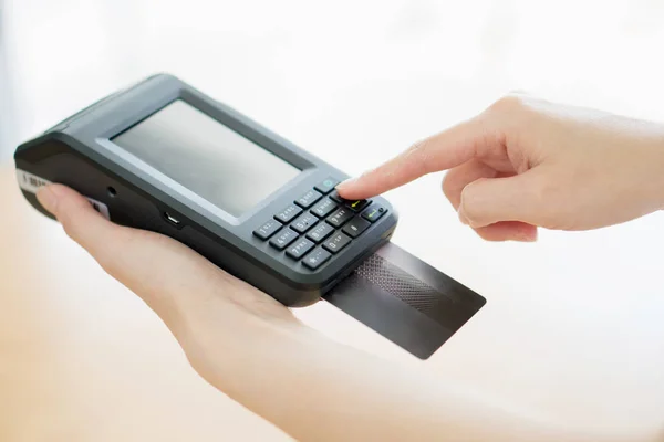 Hand with credit card swipe through terminal