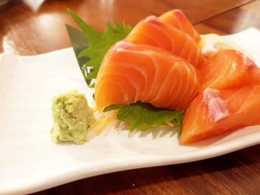 Dilimlenmiş somon sashimi ahşap masada servis
