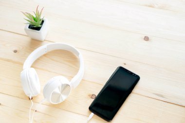 Masa ahşap üzerinde akıllı telefon ve kulaklıklar