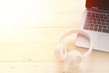 Ahşap arka plan üzerinde beyaz kulaklık ve dizüstü bilgisayar
