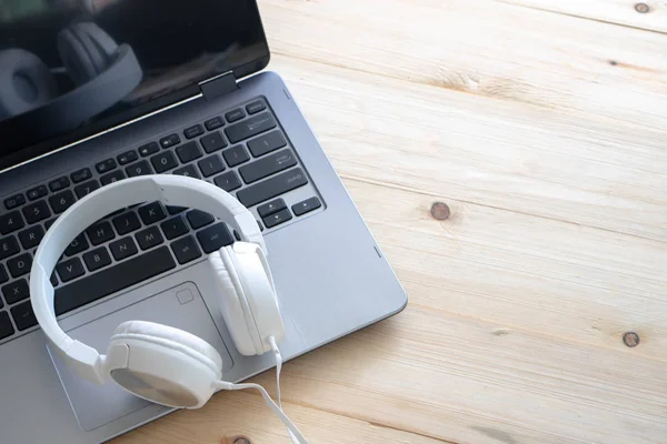 White headphone and laptop computer on wooden background