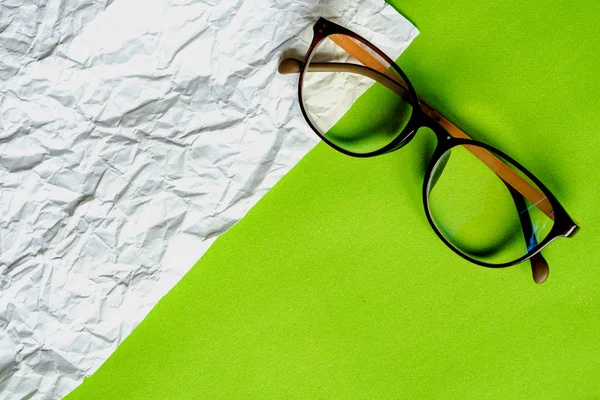 White crumpled paper and green paper. eyeglass concept.