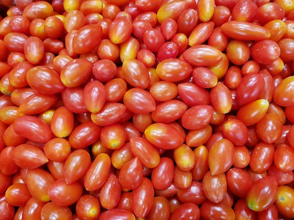 Tomates cereja empilhados, vermelhos, maduros e frescos em um mercado — Fotografia de Stock