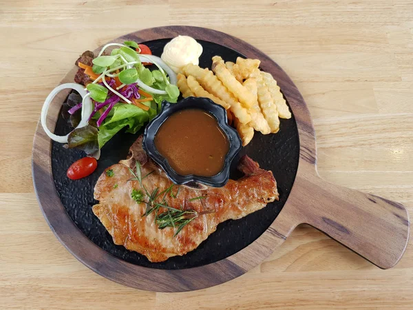 Biber sosu ve ahşap t üzerinde patates kızartması ile domuz pirzolası biftek