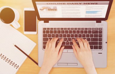 Ofisteki laptopta haber okuyan iş adamının kesilmiş görüntüsü.