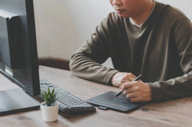 Erkek eli dijital kalem çizimi kullanıyor ve stüdyoda otururken bilgisayarla çalışıyor, tasarımcı çalışıyor 