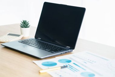 Ofis masasının yakın görüntüsü. Laptop, hesap makinesi ve kağıt işleri 