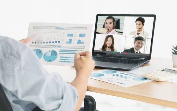 View from side of man talking to her colleagues about business plan over a video conference.