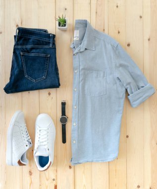 Ahşap zeminde erkek kıyafetleri ve eşyalar var.