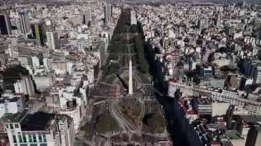 Arjantin 'in Buenos Aires' teki ana caddesi Avenida 9 de Julio üzerinde uçan hava aracı görüntüleri ikonik Obelisco de Buenos Aires 'e doğru ilerliyor. Açık bir günde gökdelenler, şehir mimarisi ve işlek caddelerle çarpıcı bir şehir..