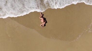 Baş döndürücü bir hava aracı, kumlu bir sahilde huzur içinde yatan hamile bir kadını yakalıyor. Görüntüler anneliğin ve doğanın güzelliğini ve huzurunu vurguluyor..