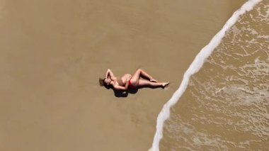 Baş döndürücü bir hava aracı, kumlu bir sahilde huzur içinde yatan hamile bir kadını yakalıyor. Görüntüler anneliğin ve doğanın güzelliğini ve huzurunu vurguluyor..