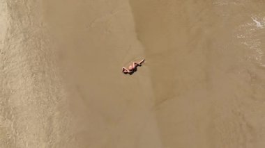 Baş döndürücü bir hava aracı, kumlu bir sahilde huzur içinde yatan hamile bir kadını yakalıyor. Görüntüler anneliğin ve doğanın güzelliğini ve huzurunu vurguluyor..