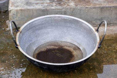 Bir dökme demir kadai (veya Karahi) yemek pişirdikten sonra, yıpranmayı bekleyen yıpranmış, yosunlu beton bir yüzey üzerinde oturmaktadır. Bu tencere Karai olarak da bilinir..