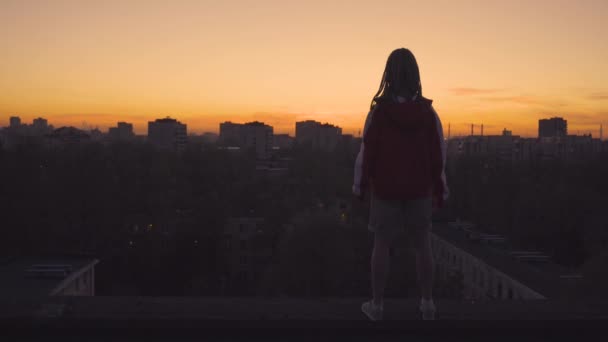 Жінка стоїть на даху і піднімається руками — стокове відео