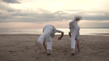 İki adam sahilde Capoeira pratik