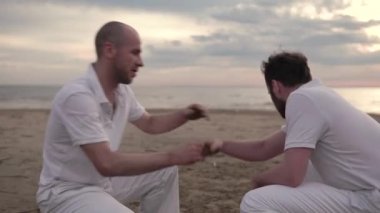 İki adam sahilde Capoeira pratik