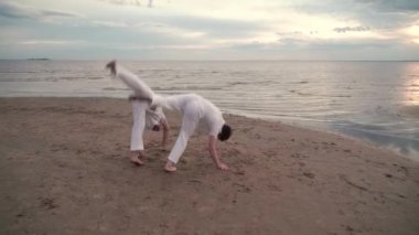 İki adam sahilde Capoeira pratik