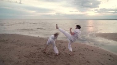 İki adam sahilde Capoeira pratik