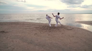 İki adam sahilde Capoeira pratik