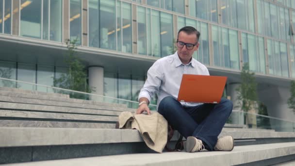 Homem sentado nas escadas e trabalhando no laptop — Vídeo de Stock