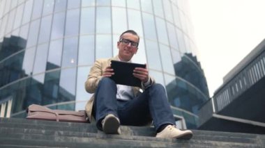 Adam merdiven oturan ve tablet PC'yi kullanma