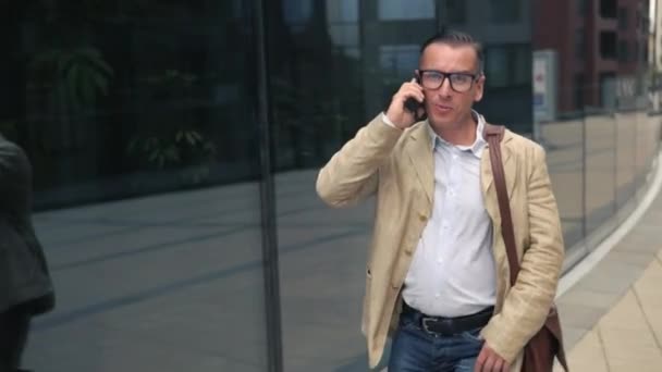 Mężczyzna idzie ulicą rozmawia przez telefon — Wideo stockowe