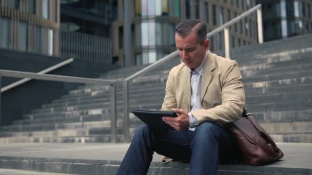 Muž sedí na schodech a použití počítače tablet pc — Stock video
