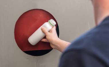 Tanınmayan kişi plastik şişeyi konteynıra atıyor.