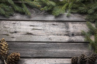 Noel ve yeni yıl dekorasyon arka plan: köknar ağacı dalları, koni ve ahşap arka plan üzerinde renkli süslemeleri. Kopya alanı ile üstten görünüm.