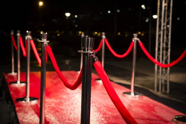 Red carpet with  barriers, velvet ropes and lights in the background