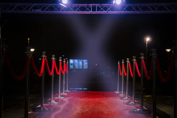 Red carpet with  barriers, velvet ropes and lights in the background