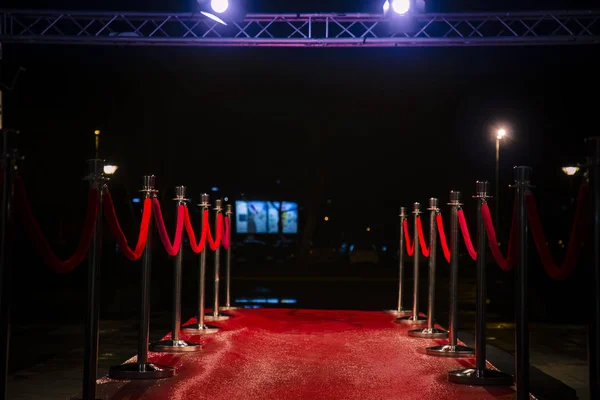 Red carpet with  barriers, velvet ropes and lights in the background