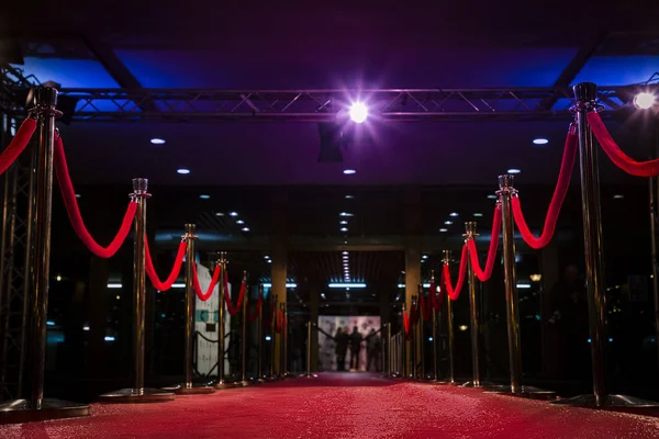 Red carpet with  barriers, velvet ropes and lights in the background