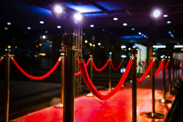 Red carpet with  barriers, velvet ropes and lights in the background