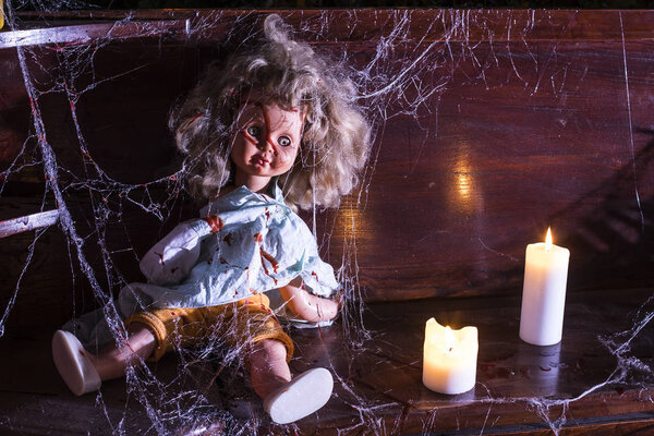 Фото старой куклы, покоящейся на старом деревянном выступе, покрытом паутиной и пылью
.