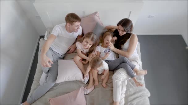 Familia acostada en la cama por la mañana con niños — Vídeo de stock