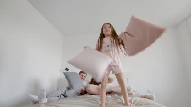 Küçük kız yatakta yastık ile eğleniyor — Stok video